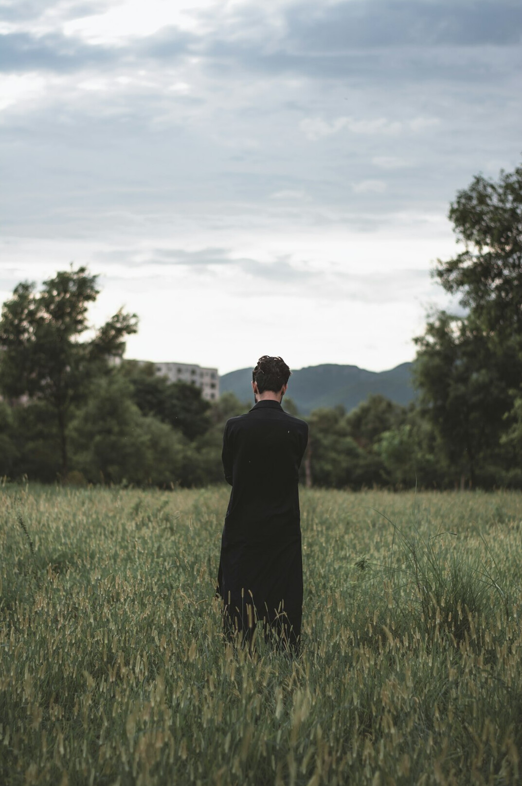 Back of a man in a dark suit standing tall with straight spine