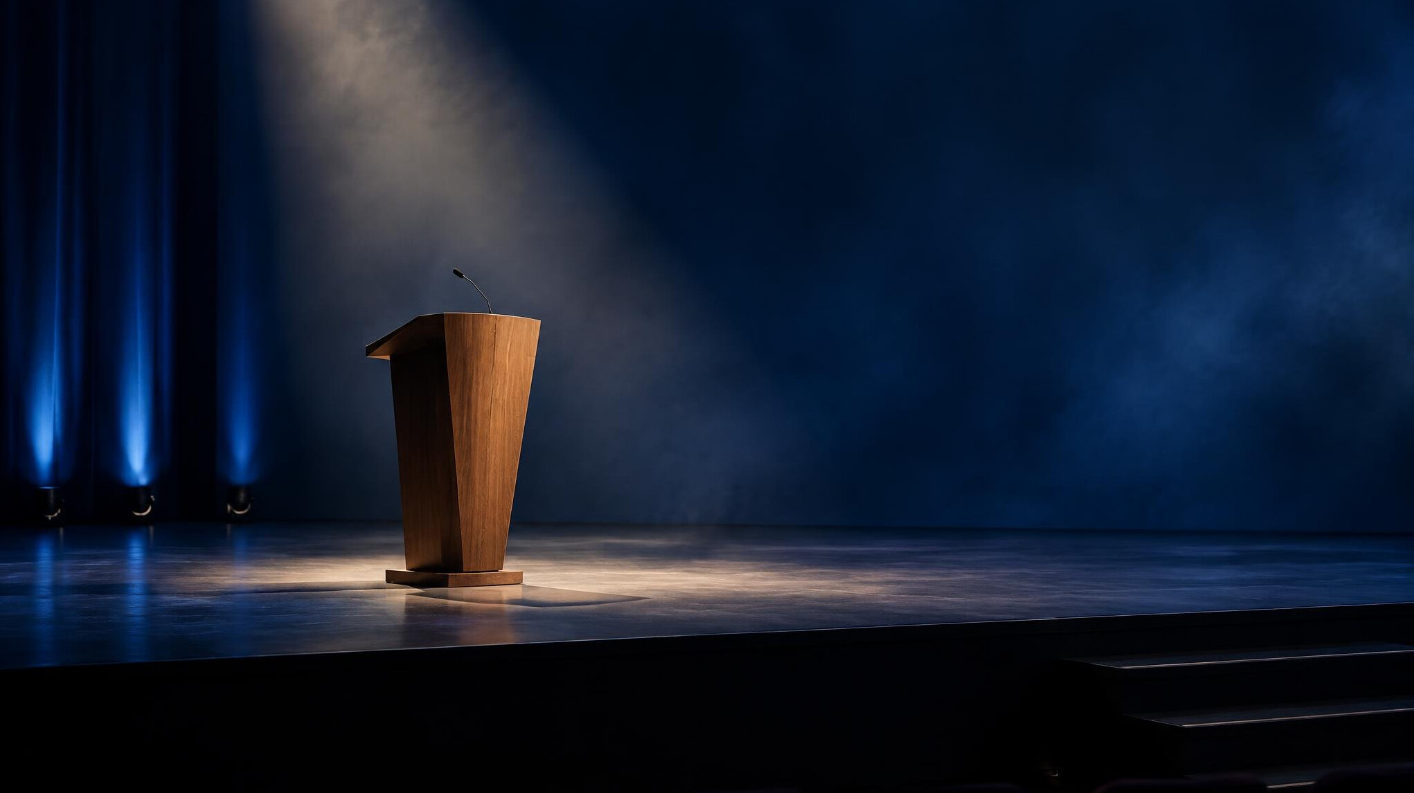Empty keynote stage with a single podium lit by a soft spotlight
